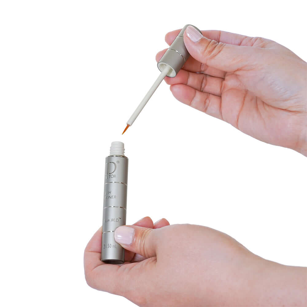 Hand holding MD Lash Factor 3-Month lash serum with visible consistency on precision-tip applicator